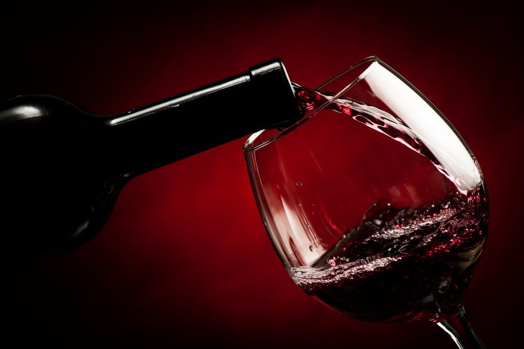 close up of red wine being poured in a wine glass