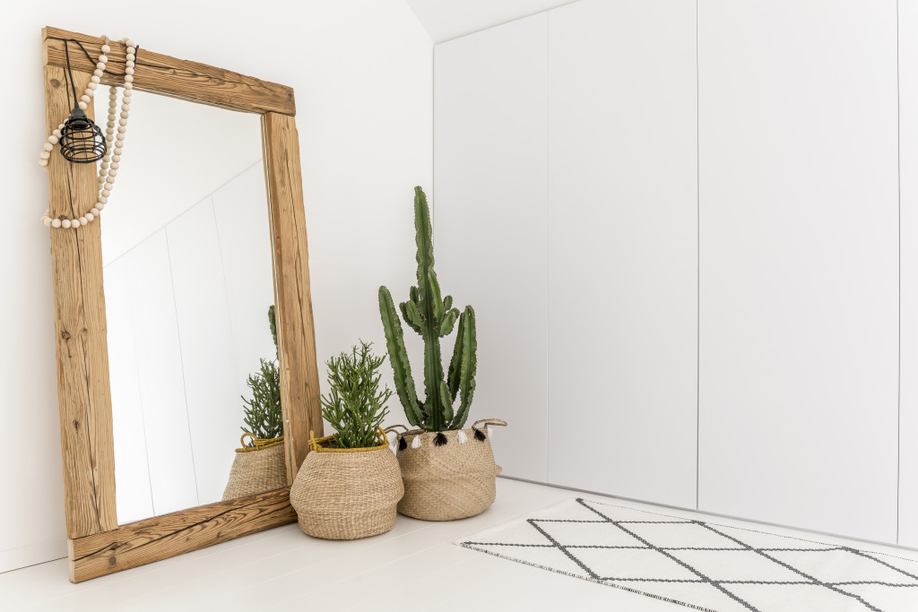 White room with mirror with wooden frame and decorative cactus