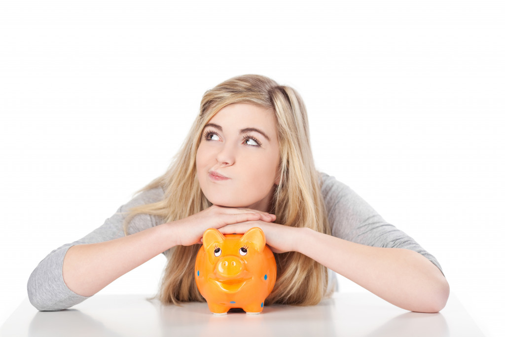 teenage girl posing with piggy bank.