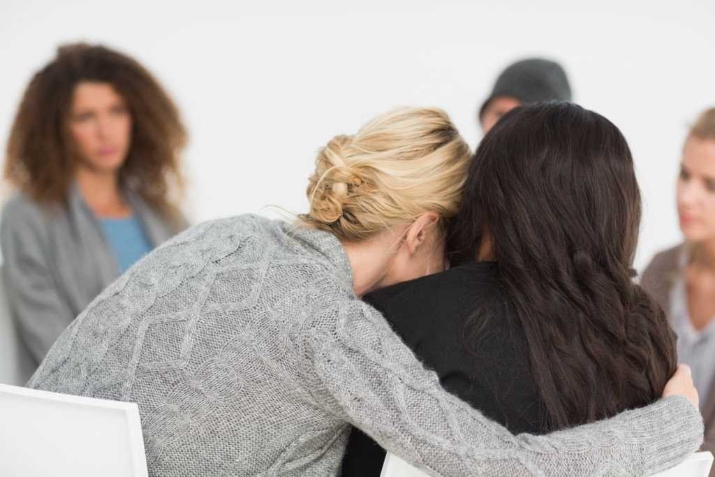 Woman hugs the woman next to her during group therapy