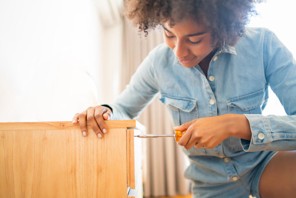 A woman using a screwdriver to repair broken furniture