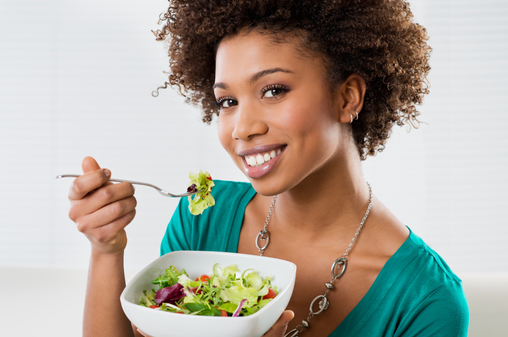 A beautiful woman eating a vegetable salad using a fork