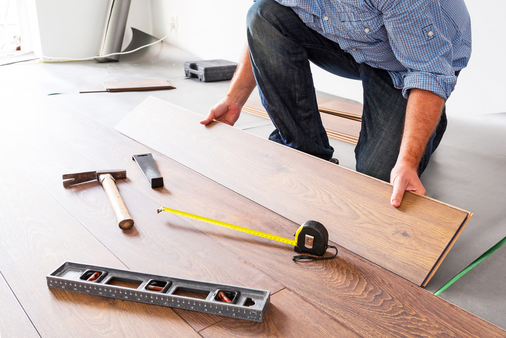 man installing custom laminated wooden flooring in a house room