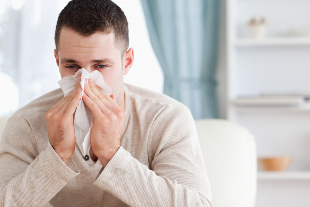 a man sneezing at home while using a tissue
