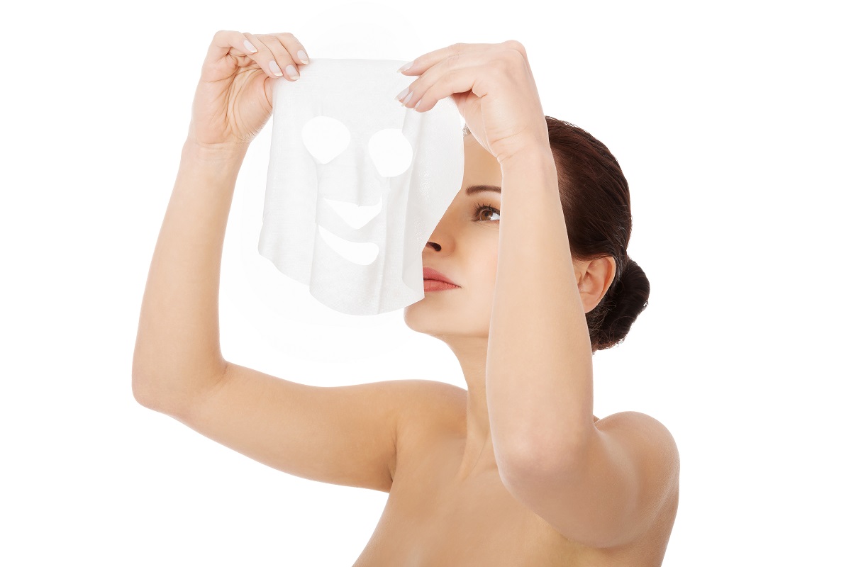 woman putting collagen mask on her face