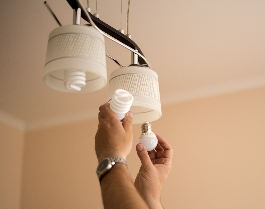 hands changing light bulbs of a hanging lamp