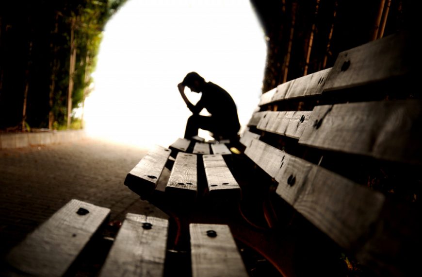 A depressed man sitting in a dark tunnel