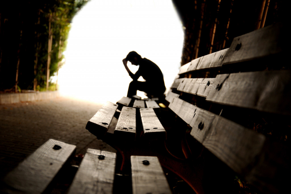 A depressed man sitting in a dark tunnel