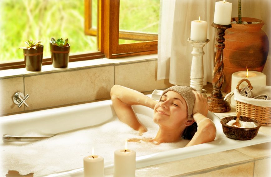 woman relaxing at home with candles in her bath tub