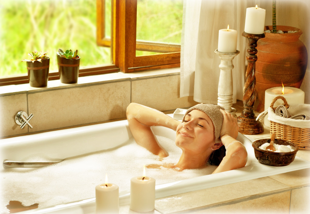 woman relaxing at home with candles in her bath tub