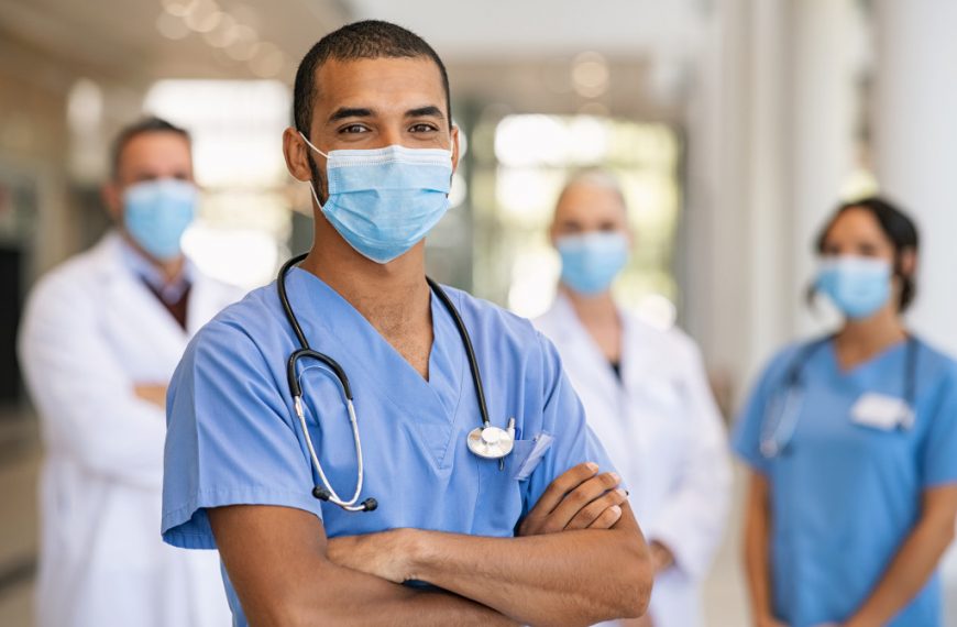 male nurse at the foreground wearing stethoscopes with doctors at the back