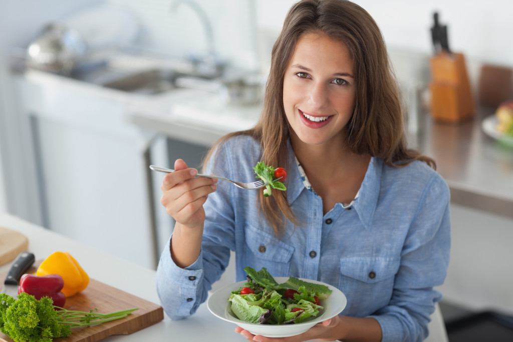 woman smiling while eating salad in the kitchen