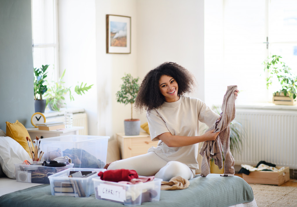 woman smiling while decluttering her clothes and belongings