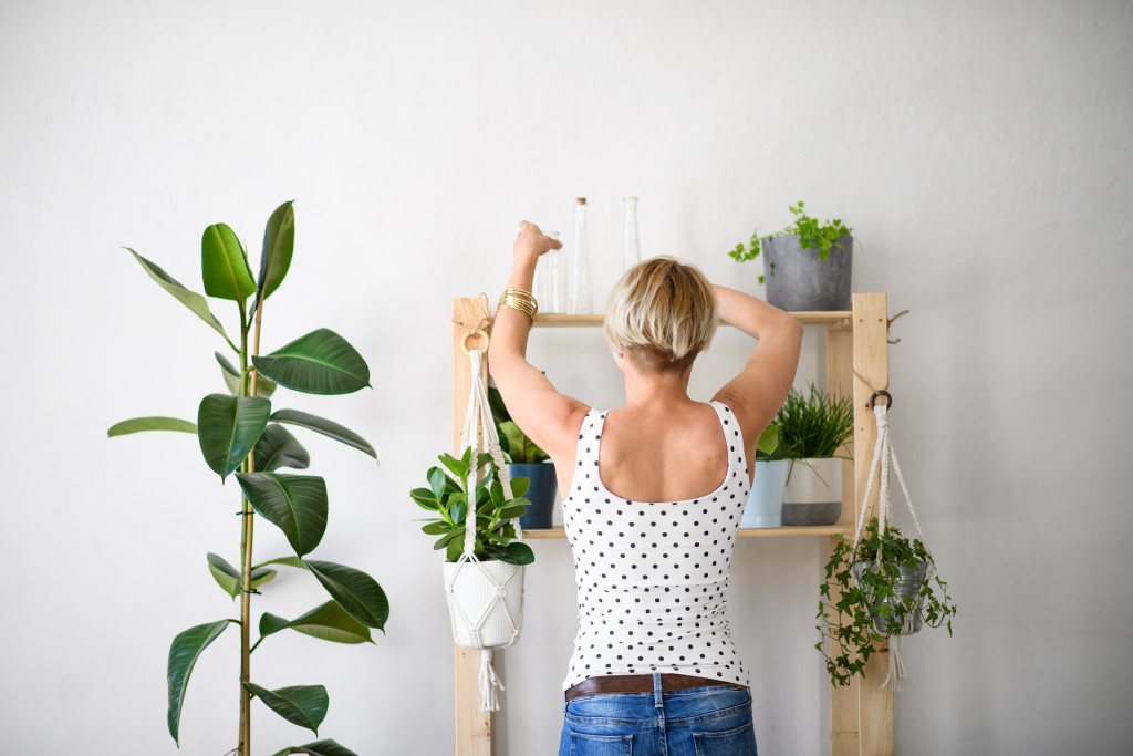 woman arranging her plant rack indoor