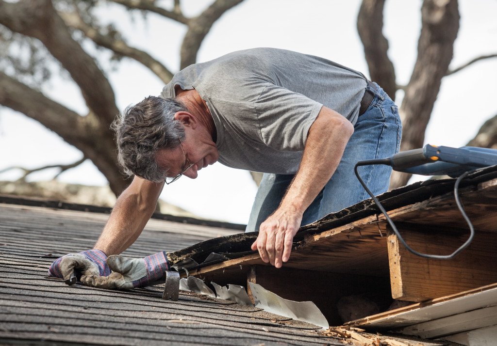 man checking the roof of an old house