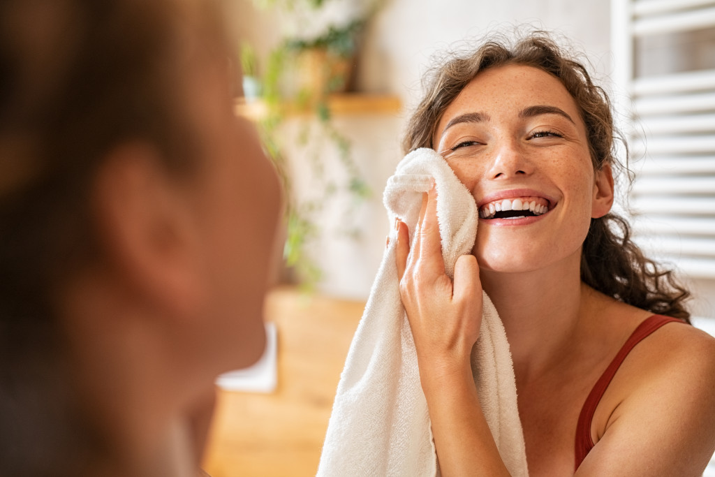 a woman wiping her face with towel